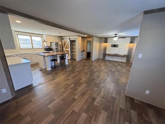 unfurnished living room featuring dark hardwood / wood-style floors, a barn door, and a textured ceiling