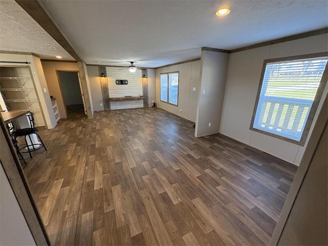 unfurnished living room featuring ceiling fan, dark hardwood / wood-style floors, and crown molding