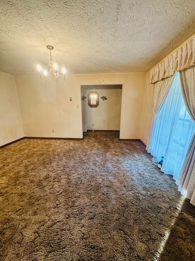 empty room with a notable chandelier, carpet flooring, and a textured ceiling