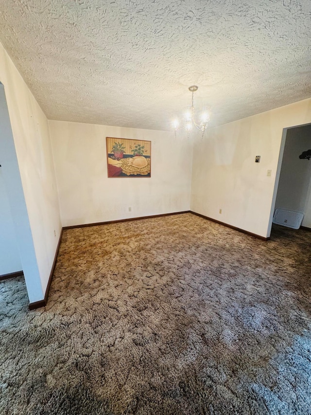 empty room with a textured ceiling, an inviting chandelier, and dark carpet