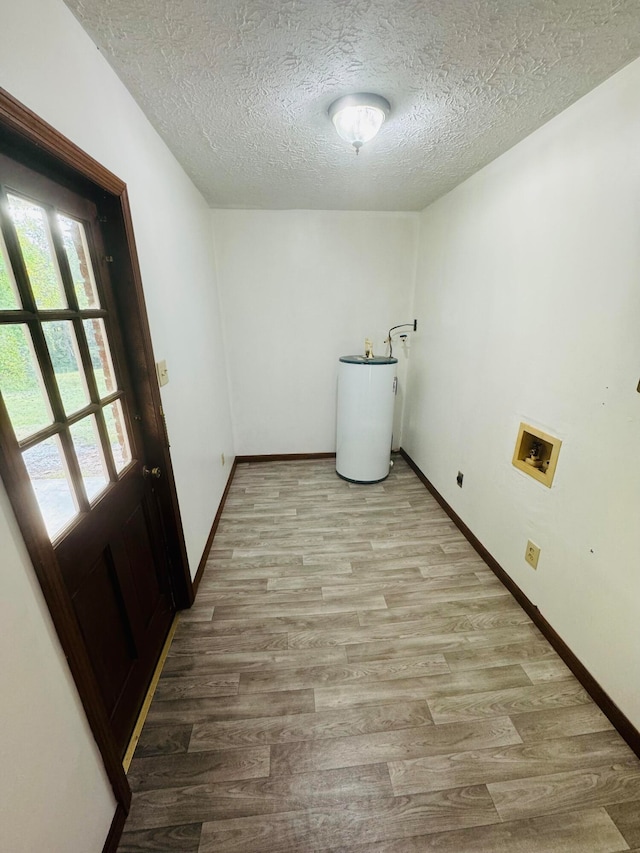 laundry area featuring hookup for a washing machine, water heater, a textured ceiling, and light hardwood / wood-style flooring