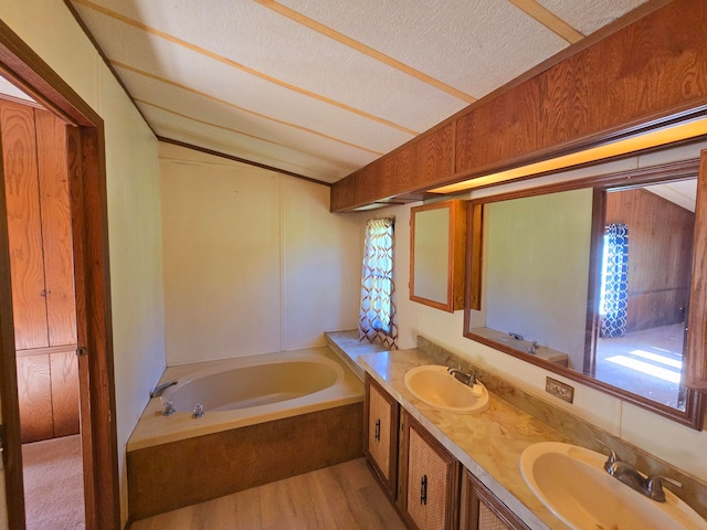 bathroom with a textured ceiling, hardwood / wood-style floors, vanity, and a washtub