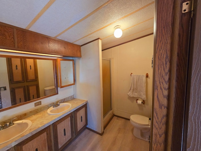 bathroom with vanity, a textured ceiling, hardwood / wood-style flooring, walk in shower, and toilet