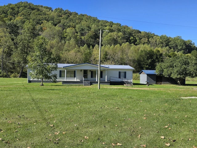 163 Eulett Ln, Vanceburg, KY 41179 - view of front facade with a front lawn, a view of trees, covered porch, a storage unit, and a metal roof