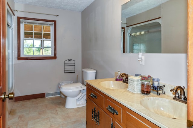 bathroom with a textured ceiling, vanity, toilet, and a shower with shower door