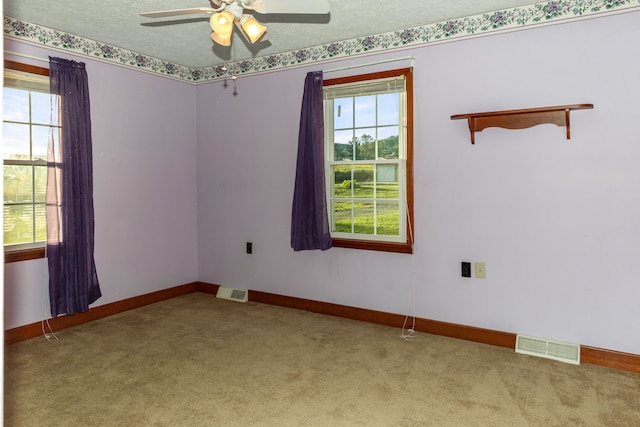 spare room featuring ceiling fan, light colored carpet, and a textured ceiling