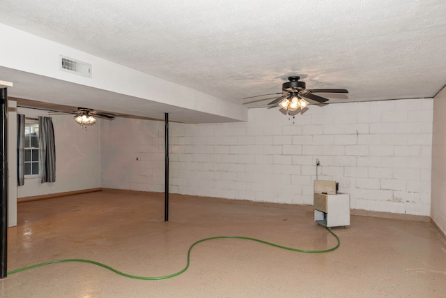 basement with ceiling fan and a textured ceiling