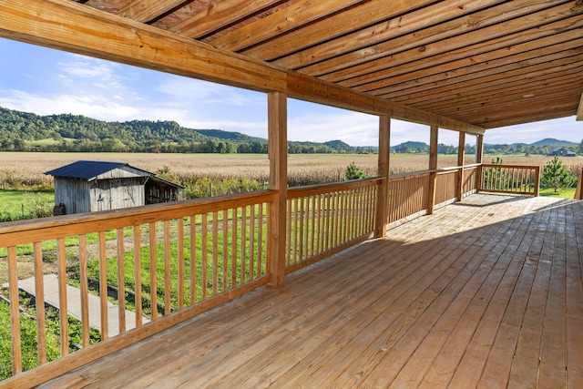 wooden deck with a storage shed, a mountain view, a rural view, and a yard