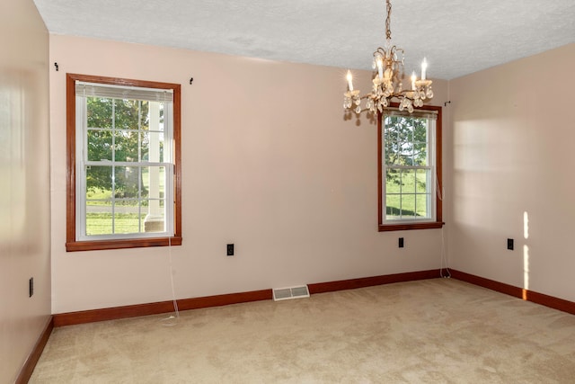 unfurnished room with light carpet, a chandelier, and a textured ceiling