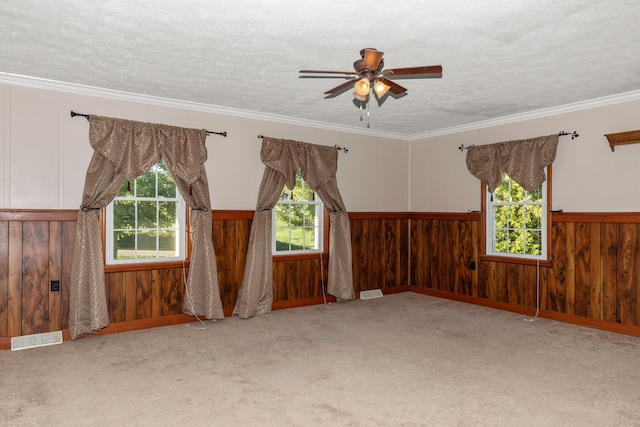 unfurnished room with ceiling fan, a textured ceiling, wooden walls, and light carpet