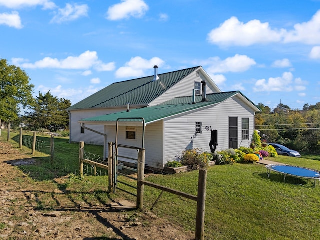 rear view of house featuring a lawn and a trampoline