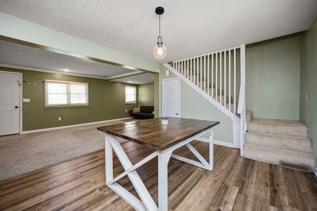 unfurnished dining area featuring a textured ceiling, ornamental molding, and hardwood / wood-style flooring