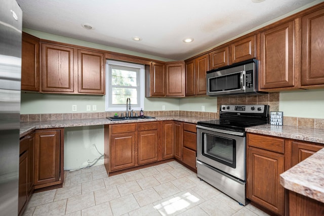 kitchen with light stone countertops, appliances with stainless steel finishes, and sink