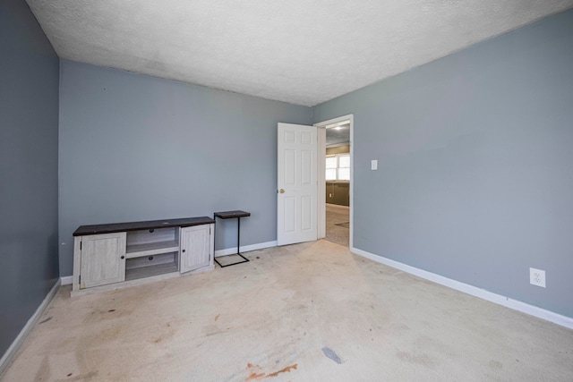 unfurnished room with a textured ceiling and light carpet