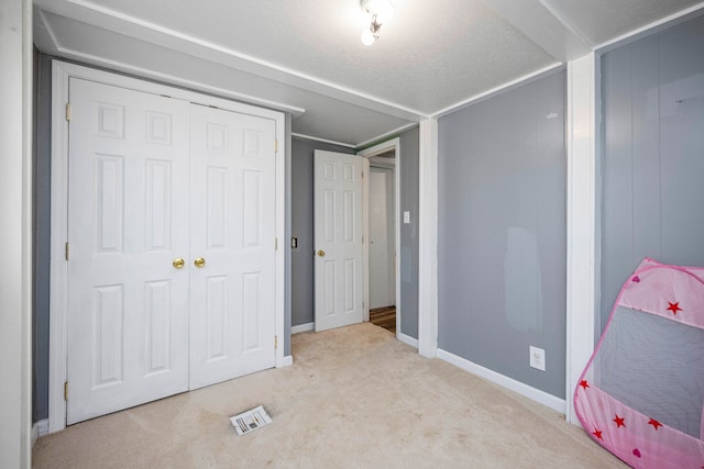 bedroom featuring a textured ceiling, light colored carpet, and a closet