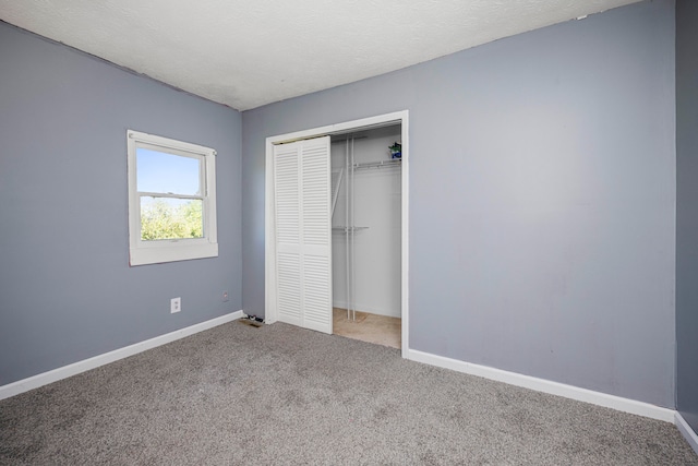 unfurnished bedroom featuring light colored carpet, a textured ceiling, and a closet