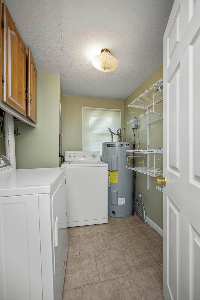 clothes washing area featuring cabinets, water heater, a textured ceiling, and washing machine and clothes dryer