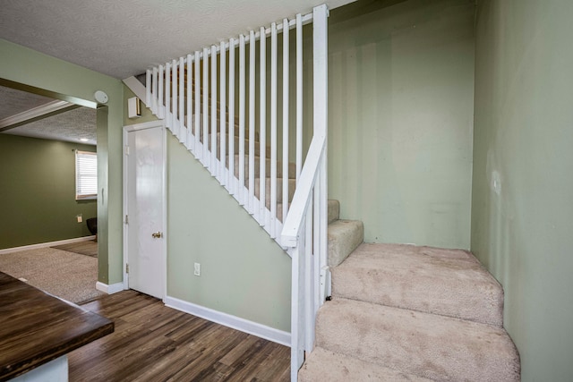 staircase featuring a textured ceiling and hardwood / wood-style floors