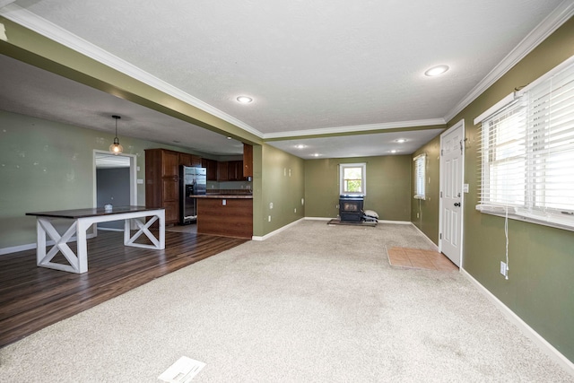 living room featuring a wood stove, wood-type flooring, plenty of natural light, and crown molding