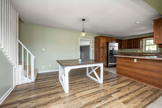 kitchen with pendant lighting, sink, stainless steel fridge with ice dispenser, and dark wood-type flooring