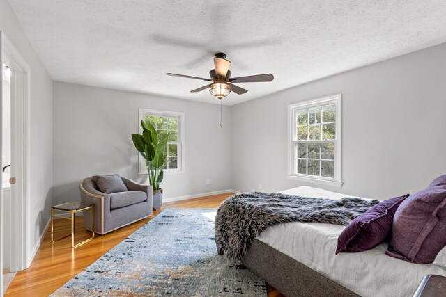 bedroom featuring ceiling fan, hardwood / wood-style flooring, and a textured ceiling