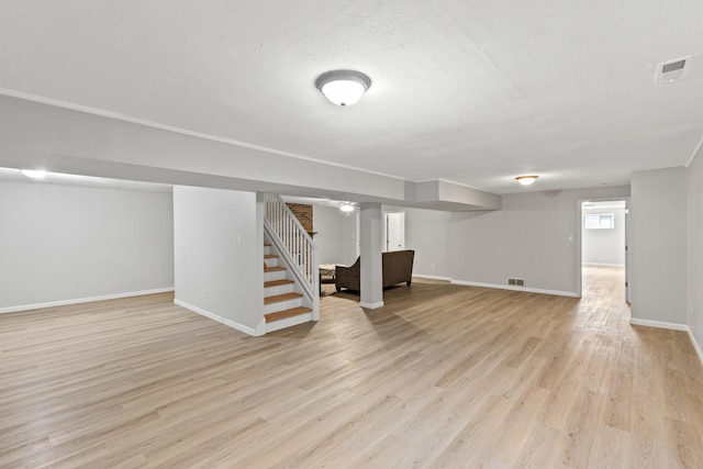 basement with a textured ceiling and light hardwood / wood-style flooring