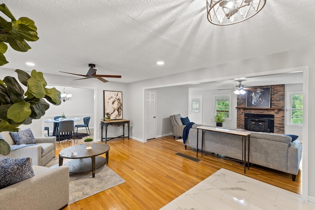 living room with hardwood / wood-style flooring, ceiling fan with notable chandelier, and a healthy amount of sunlight