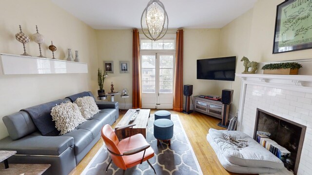 living room with light wood-type flooring, a fireplace, and an inviting chandelier