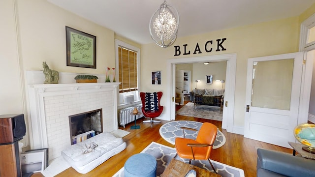 living room featuring hardwood / wood-style flooring, a notable chandelier, cooling unit, a fireplace, and radiator