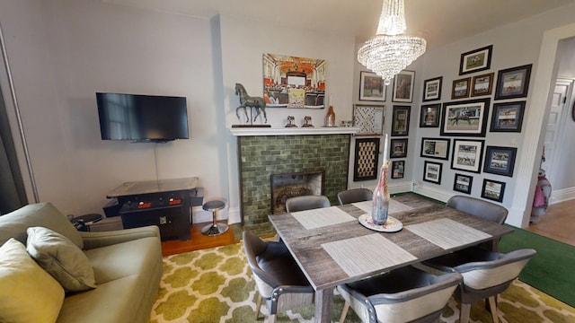 dining room with wood-type flooring, a notable chandelier, and a brick fireplace