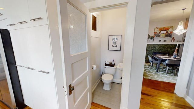 bathroom with a brick fireplace, hardwood / wood-style floors, and toilet