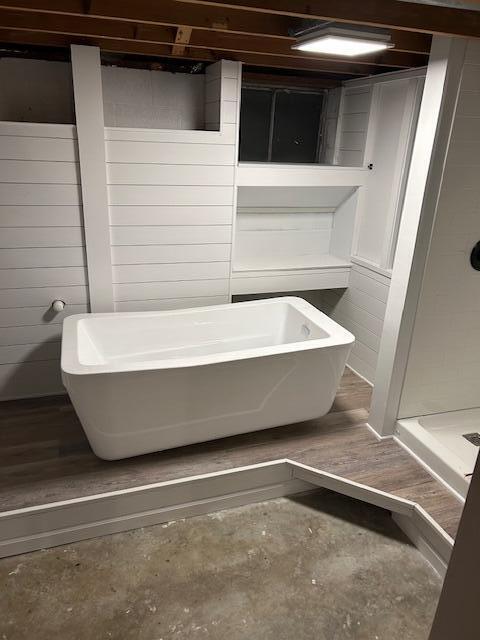 bathroom featuring a bath and concrete floors