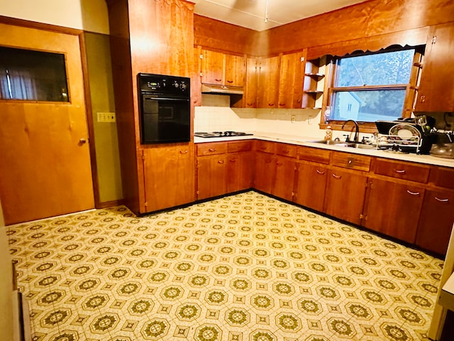 kitchen featuring white gas stovetop, sink, black oven, and backsplash