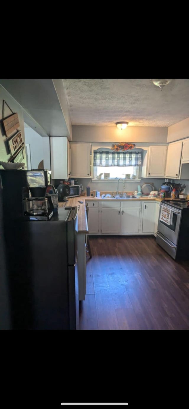 kitchen with white cabinets, dark wood-type flooring, a textured ceiling, and stainless steel electric stove