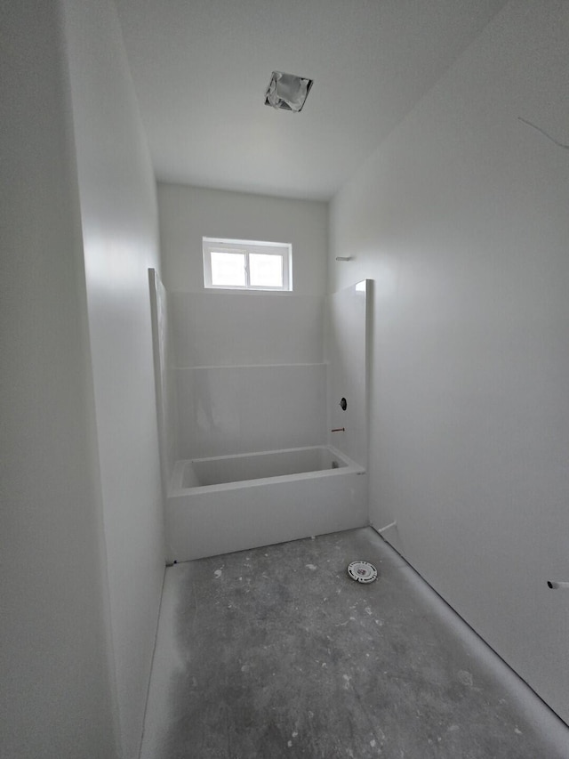 bathroom with concrete floors and a tub