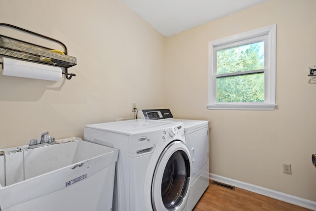 laundry area with sink, separate washer and dryer, and light wood-type flooring