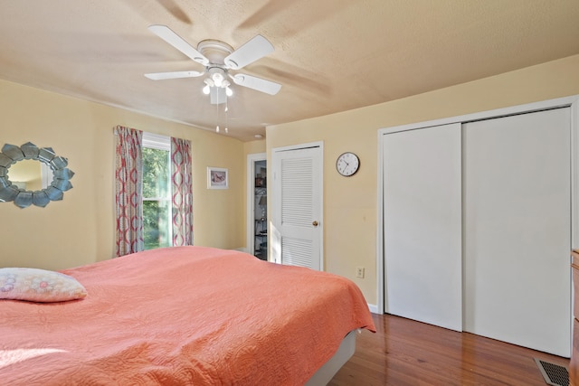 bedroom featuring ceiling fan, multiple closets, and wood-type flooring