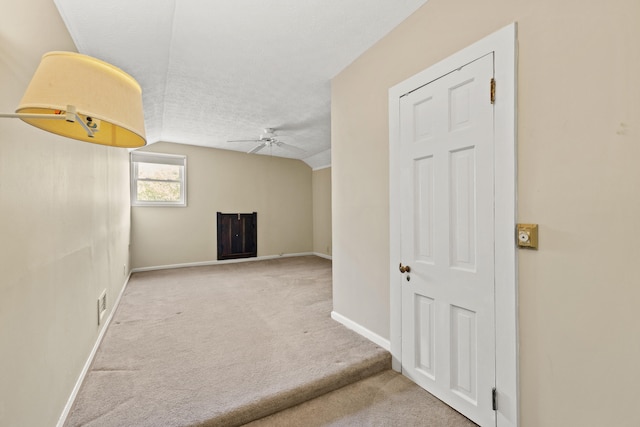 empty room with lofted ceiling, light carpet, a textured ceiling, and ceiling fan