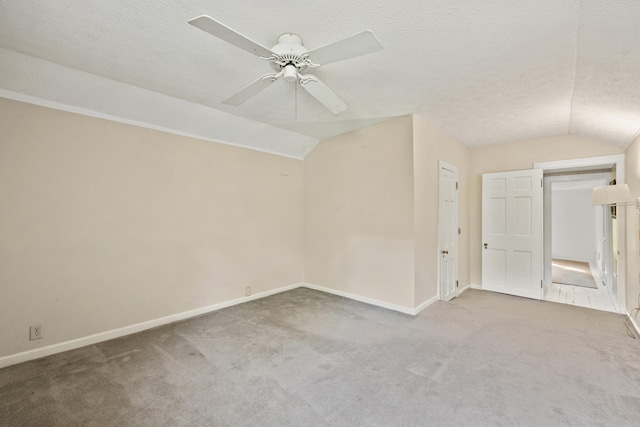 additional living space with lofted ceiling, a textured ceiling, carpet, and ceiling fan