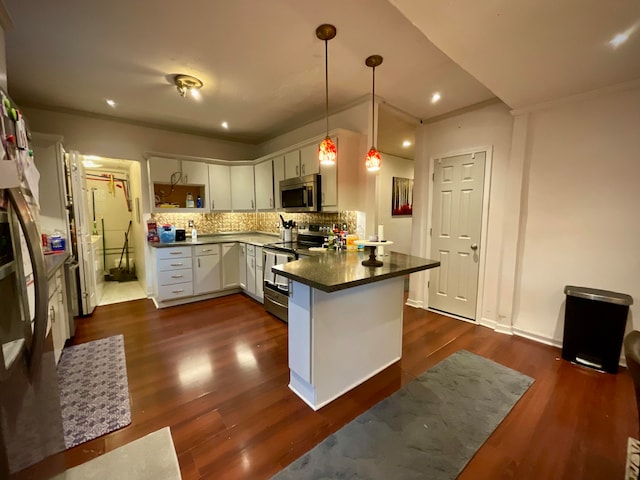 kitchen featuring appliances with stainless steel finishes, dark wood-type flooring, white cabinets, kitchen peninsula, and decorative light fixtures