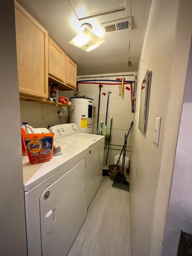 washroom featuring washer and dryer, electric water heater, and cabinets