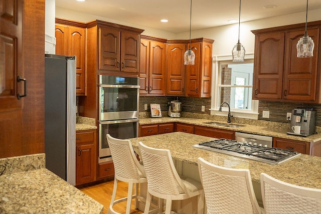 kitchen featuring pendant lighting, sink, a kitchen bar, decorative backsplash, and appliances with stainless steel finishes