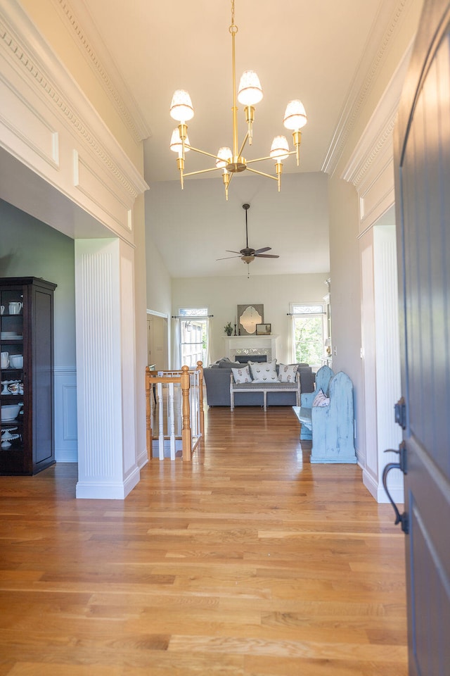 interior space with lofted ceiling, ornamental molding, an inviting chandelier, and light hardwood / wood-style flooring