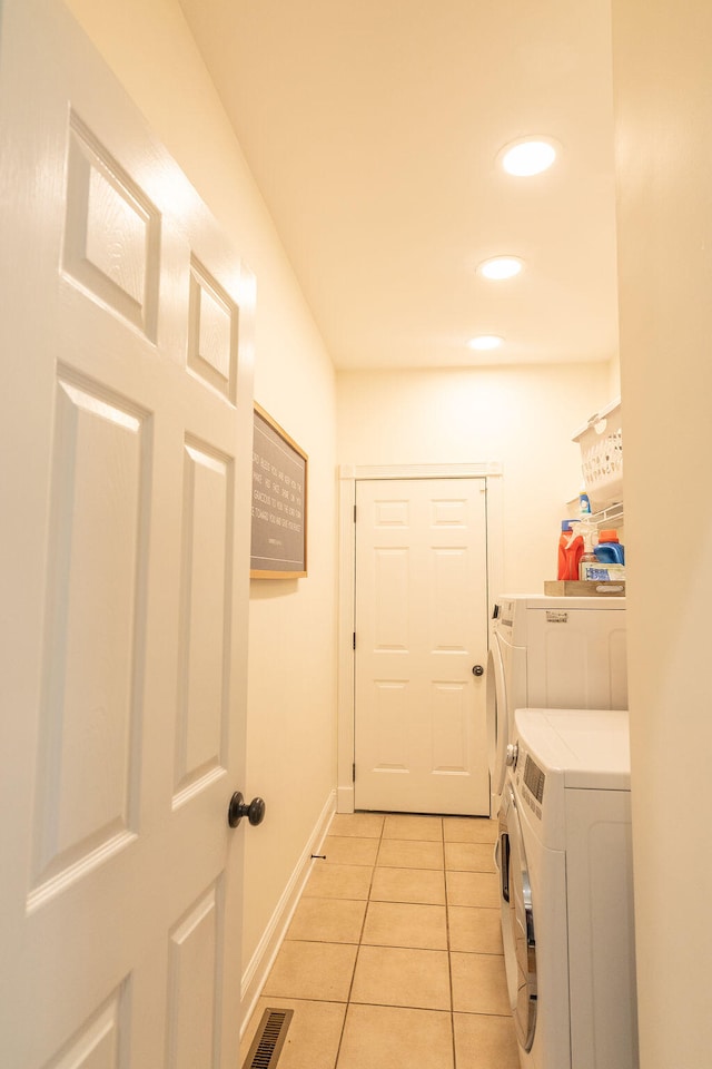 clothes washing area featuring light tile patterned floors and washer and clothes dryer