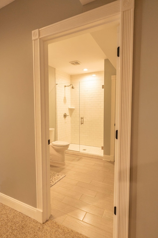 bathroom with toilet and a shower with shower door