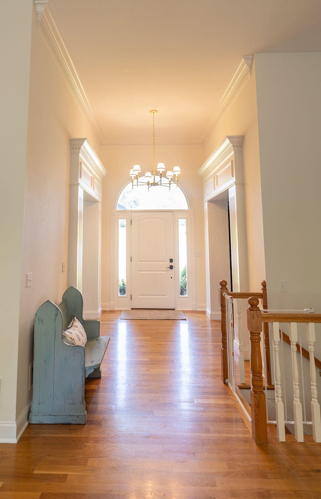 foyer with wood-type flooring, a chandelier, and ornamental molding