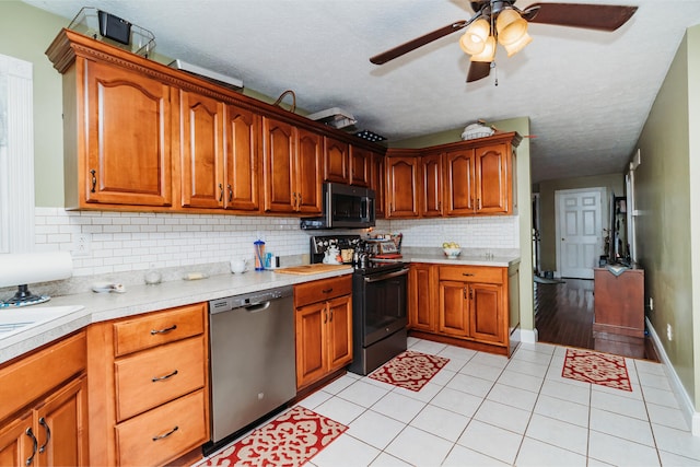 kitchen with ceiling fan, a textured ceiling, stainless steel appliances, and decorative backsplash