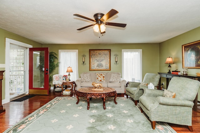 living room with a textured ceiling, ceiling fan, and dark hardwood / wood-style flooring