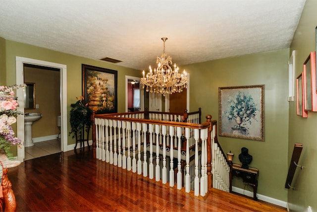 hallway with a textured ceiling, a chandelier, and hardwood / wood-style flooring