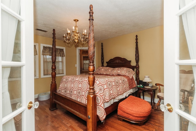 bedroom featuring an inviting chandelier, hardwood / wood-style flooring, and a textured ceiling